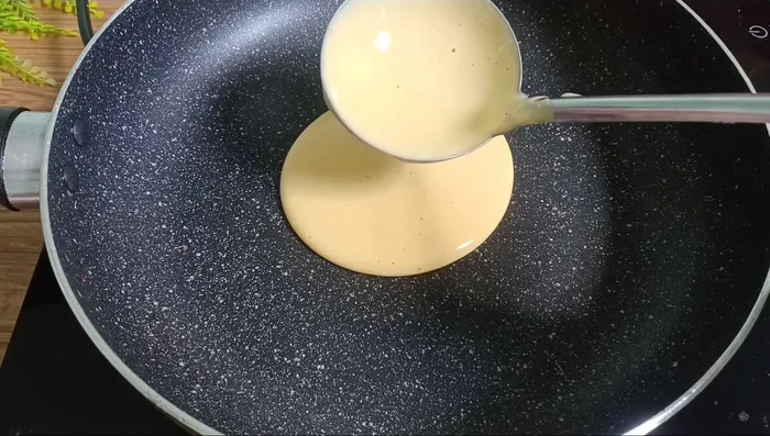 Đổ từng muỗng hỗn hợp bánh vào chảo, rán đến khi mặt bánh nổi bong bóng và vàng đều. (373.31)