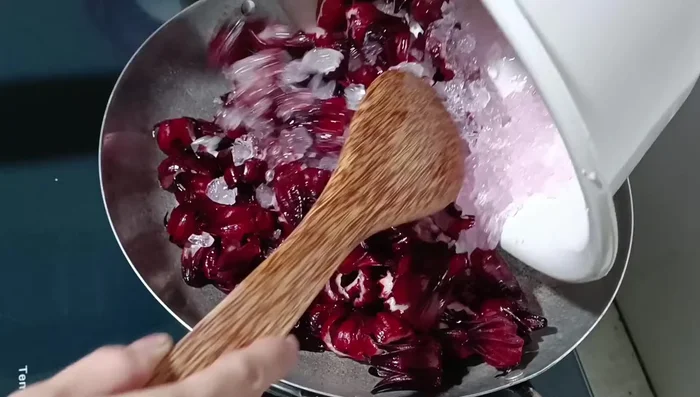 Cho hỗn hợp hoa atiso và đường vào chảo, đun lửa lớn cho đường tan nhanh. Sau đó, vặn lửa vừa. [185.7]