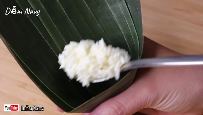Gói bánh: Cho nếp, nhân đậu xanh vào lá, gói lại và buộc chặt bằng dây cotton. (389.129)