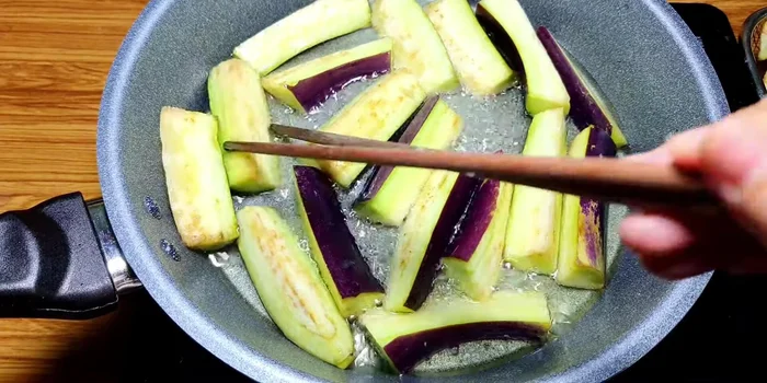 Chiên sơ cà tím trong chảo dầu nóng đến khi hơi vàng. Không chiên quá lâu để cà tím không bị mềm nhũn.