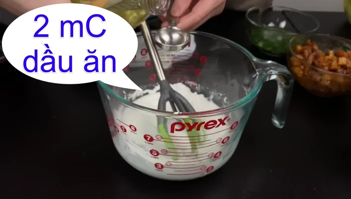Thêm 2 muỗng canh dầu ăn vào hỗn hợp bột.