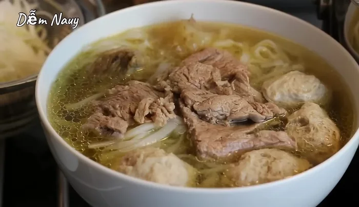 Chan nước dùng nóng vào tô phở.