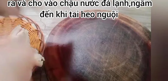 Tai heo luộc chín vớt ra, cho vào chậu nước đá lạnh ngâm đến khi nguội để tai heo trắng và giòn hơn, sau đó vớt ra để ráo và cắt thành từng miếng mỏng.