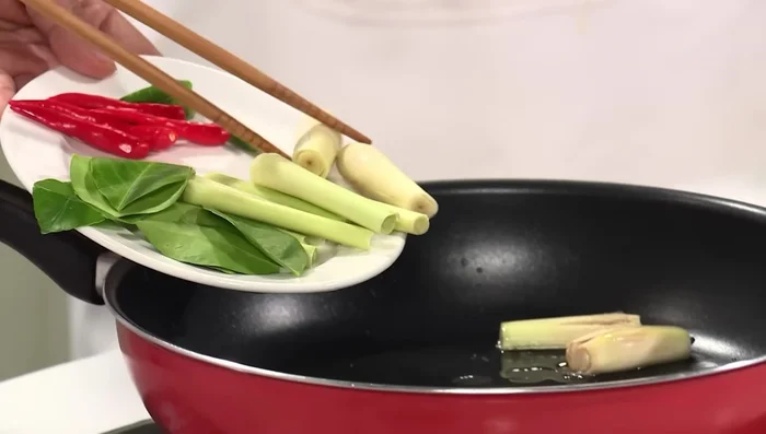 Phi thơm sả, lá chanh, ớt trong chảo với 2 muỗng canh dầu ăn.