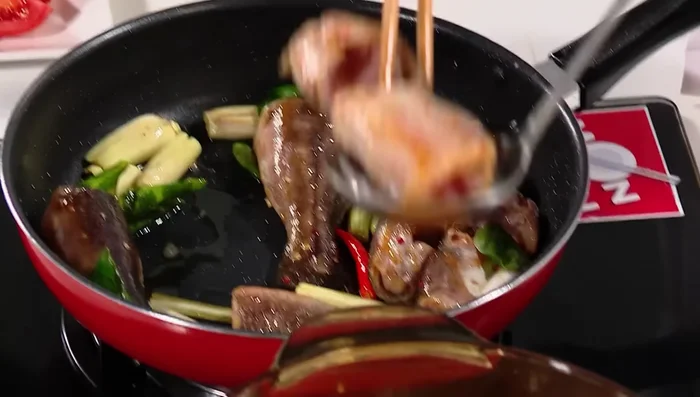 Cho cá đã xào vào nồi nước lẩu đang sôi.