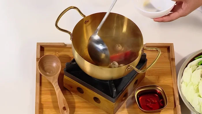 Múc lẩu ra nồi, trang trí rau ôm và các nguyên liệu khác.