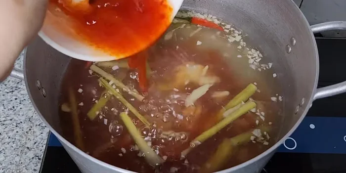 Khi nước lẩu sôi, cho hỗn hợp gia vị vào nồi, khuấy đều.