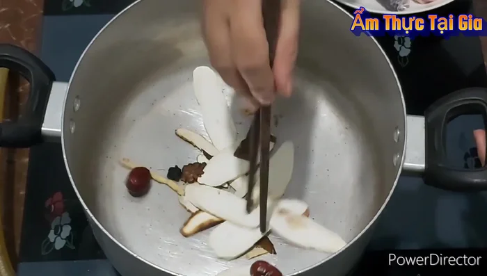 Nấu nước lẩu: cho thuốc bắc vào nồi nóng rang 2-3 phút cho thơm. Thêm xương gà, sả, hành tím nướng, bắp Mỹ vào, rang sơ.