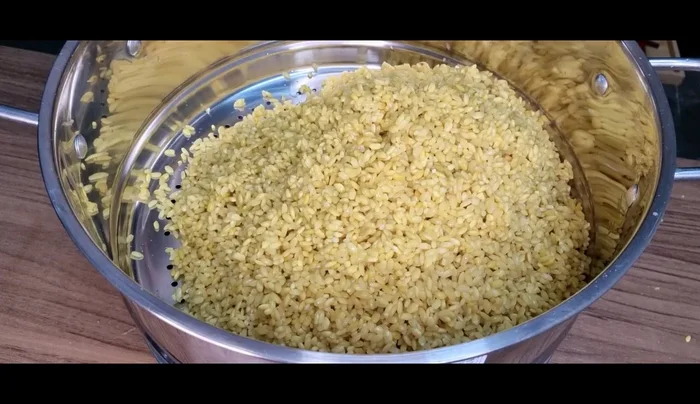 Cho hỗn hợp gạo vào khay hấp, dàn đều và tạo vài lỗ thoát hơi nước.