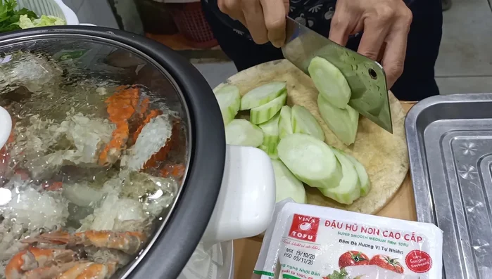 Cho đậu hũ non, nấm vào nồi lẩu đang sôi.