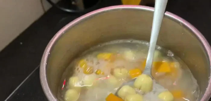 Thêm bí đỏ vào nồi cháo, nấu cho đến khi bí đỏ chín mềm.
