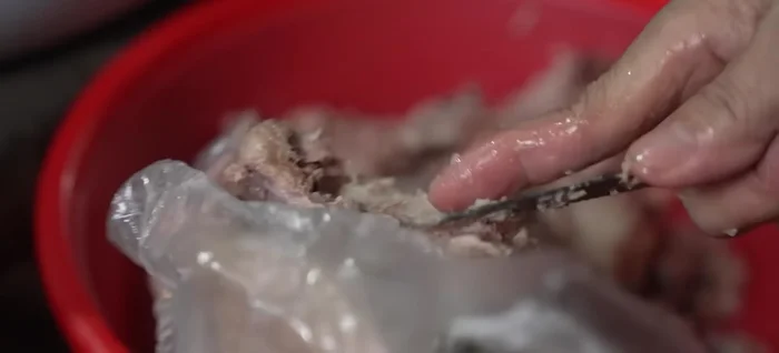 Vo gạo thật sạch, cho vào nồi cùng nước ninh xương, khuấy đều cho gạo nở và hơi đặc [60.6].