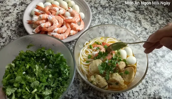 Cho hành lá, ngò rí thái nhỏ vào tô bánh canh khi tắt bếp.