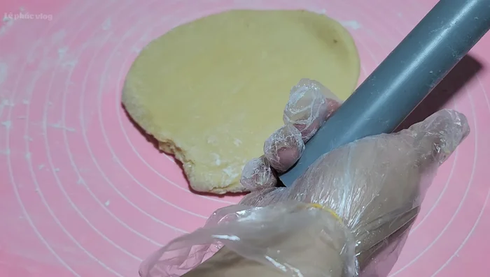 Cán mỏng bột, rắc mè trắng lên bề mặt, cán lại để mè dính vào bột. Lặp lại với mặt còn lại.