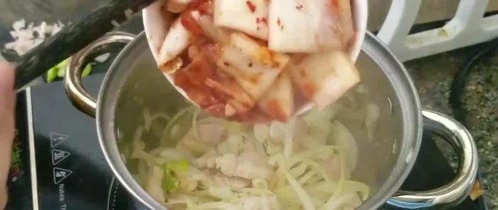 Sau khoảng 2 phút, cho kim chi vào đảo đều với thịt và hành tây.