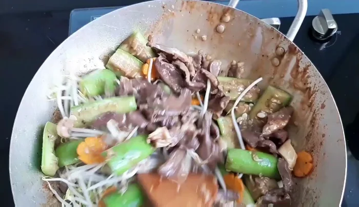 Thêm mướp, cà rốt và giá đỗ: Cho mướp, cà rốt và giá đỗ vào chảo, xào cùng tim heo đến khi các nguyên liệu chín.