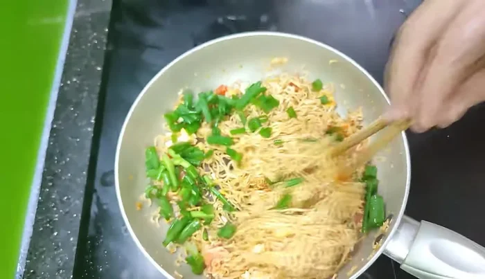 Thêm hành lá vào, đảo nhẹ cho hành lá chín.