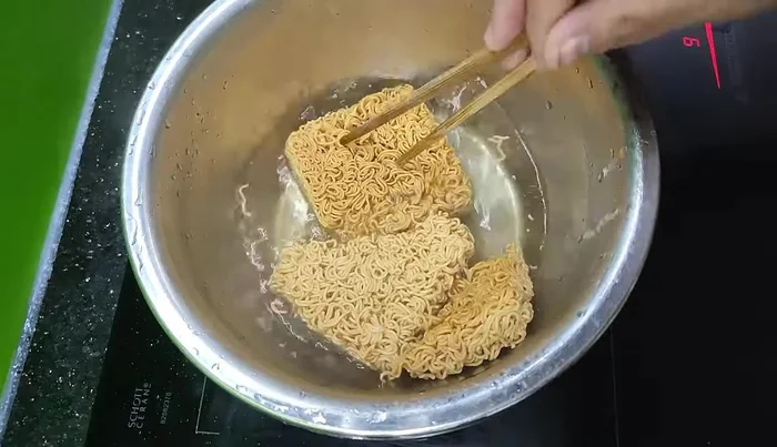 Rửa sạch mì với nước lạnh để mì săn lại và bớt dầu.