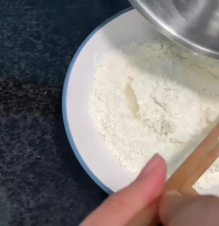 Cho từ từ nước sôi vào 150 gam bột mì, khuấy đều đến khi hỗn hợp không còn khô.