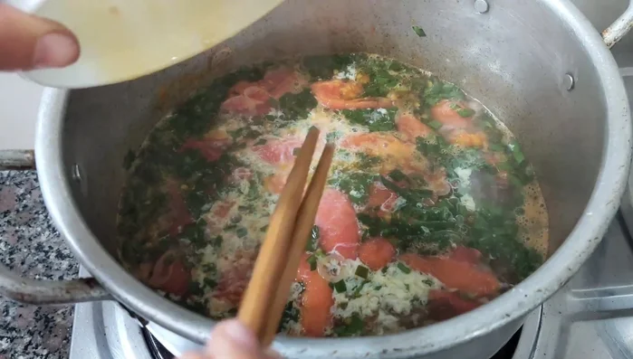 Sau khi canh sôi được 2 phút, cho hỗn hợp trứng đã đánh tan vào, dùng đũa quấy đều. Đun đến khi canh sôi lại là được.