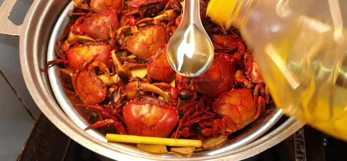 Sau khi hấp xong, cho 1 muỗng canh dầu ăn vào, thoa đều lên mặt cua để cua có màu đẹp hơn.