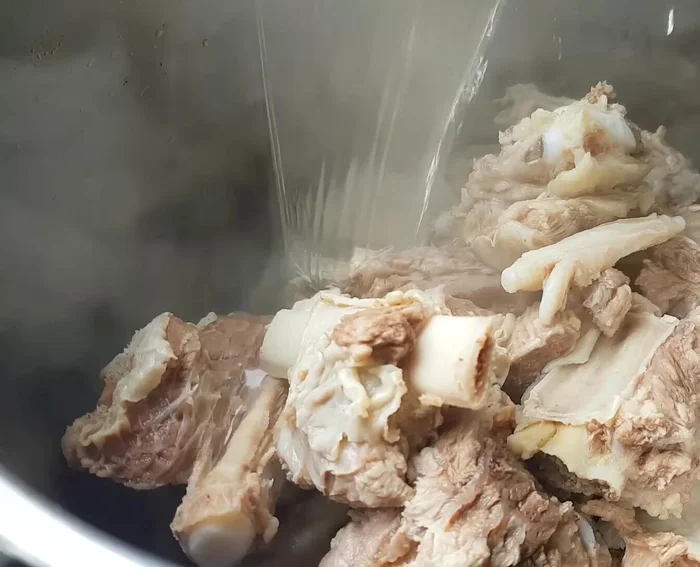 Cho sườn bò vào nồi nước sôi (4 lít), đun sôi rồi hớt bọt. Thêm củ hành tím, tỏi, gừng đập dập, sả đập dập (để riêng 2 nhánh) và phần sả còn lại đã đập dập và tước nhỏ vào nồi.