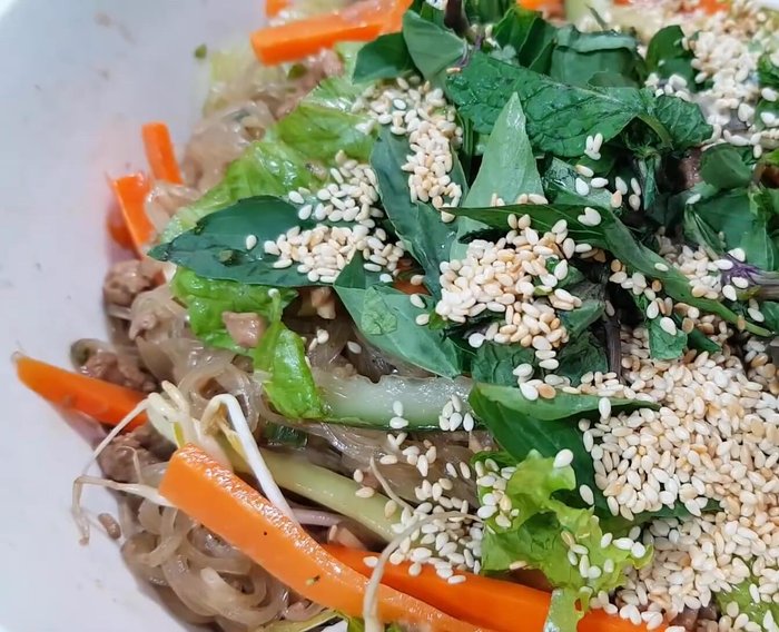 Thêm rau thơm, mè rang vào trộn đều.