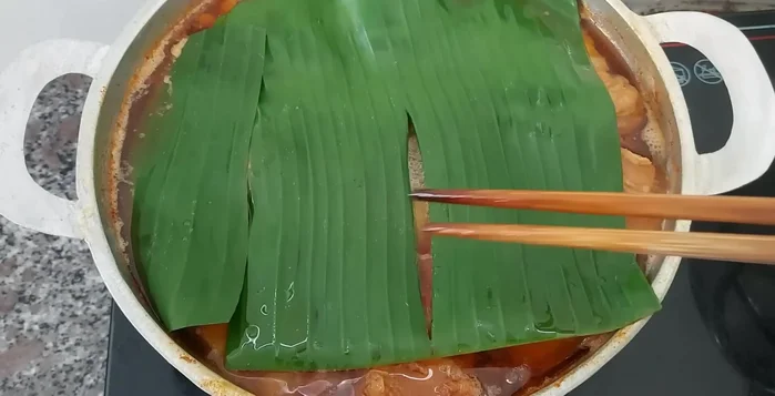 Đậy lá chuối (hoặc giấy nến) lên trên, đun nhỏ lửa thêm 30 phút.