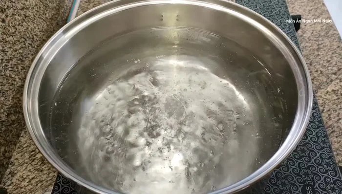 Nấu 3.5 lít nước sôi, cho xương gà và đường vào. Đun lửa lớn cho nước sôi trở lại.