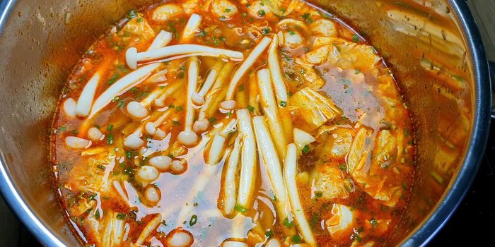 Khi nước dùng sôi trở lại, cho nấm, mực, tôm vào.