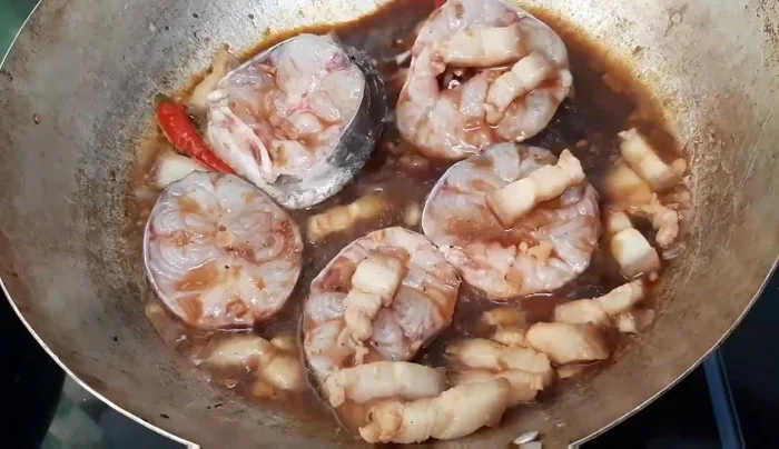 Rưới nước sốt: Trong quá trình kho, thỉnh thoảng dùng muôi múc nước sốt rưới đều lên cá.