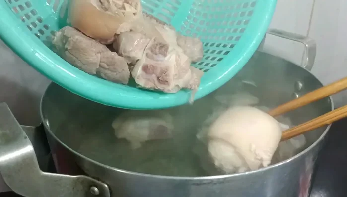Cho chân giò, thịt bắp vào nồi nước, đun sôi, hớt bọt.