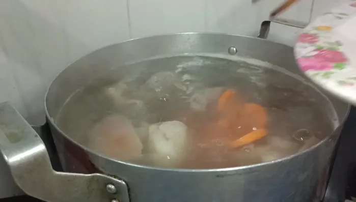 Cho cà rốt vào nồi nước súp đang sôi.