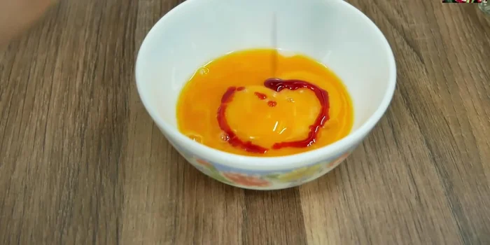 Cho thêm dầu mè và dầu màu điều (tùy chọn) lên mặt trứng. Hấp thêm 5 phút nữa.