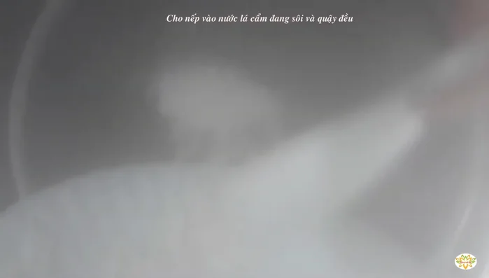 Cho nếp vào nồi nước lá cẩm đang sôi, khuấy đều cho nếp ngấm đều màu.