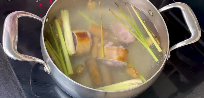 Bắt lên bếp một nồi nước, cho gừng thái lát và 1 cây sả đập dập vào. Chần đuôi bò và gân bò để khử mùi hôi.