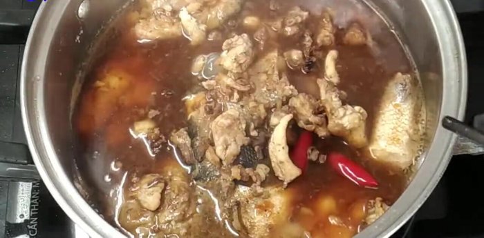 Đổ nước kho lên cá, thêm tóp mỡ (tùy chọn) và ớt bột (tùy chọn).