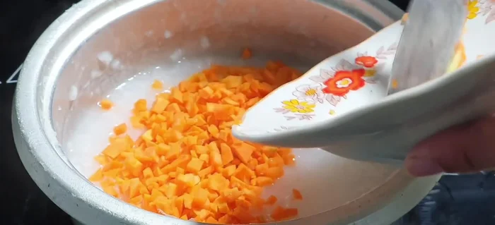 Cho cà rốt vào nồi cháo, nấu đến khi cà rốt chín mềm.