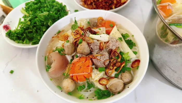 Cho hành phi và tiêu xay lên trên. Múc giò heo, măng ra tô riêng hoặc dùng nồi lẩu để thưởng thức cùng bún.