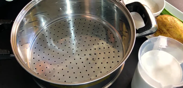 Cho gạo nếp vào xửng hấp, dàn đều và tạo lỗ nhỏ để hơi nước dễ dàng luộc chín.