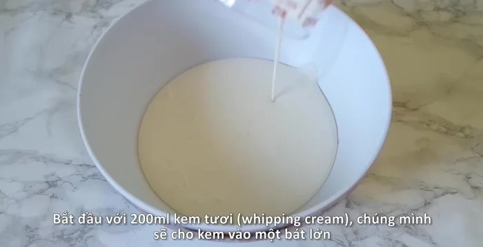 Cho 200ml kem tươi vào tô trộn lớn. Thêm 1 thìa canh đường trắng và dùng máy đánh trứng đánh bông kem đến khi mềm mịn.