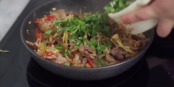 Cho rau ngổ, mùi tàu vào, rắc tiêu xay. Xào thêm 5 giây rồi tắt bếp.