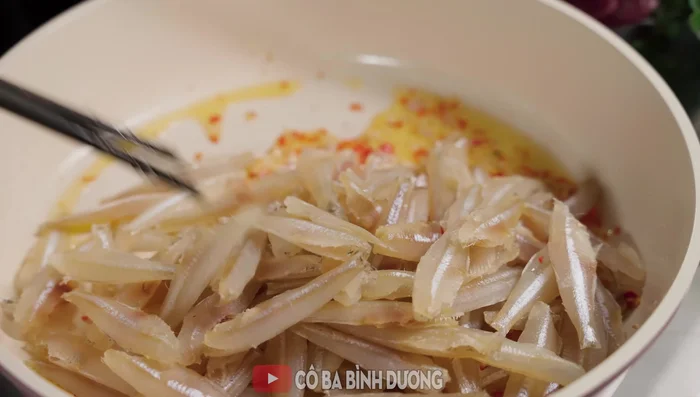 Cho cá vào chảo hành tỏi đã phi, đảo đều cho thơm. Tắt bếp, cho nước màu đường vào, trộn đều.