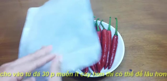 Chọn ớt tươi, chín đều, rửa sạch. Cho ớt vào túi nilông, để vào tủ đá 30 phút để giảm độ cay (77.36).