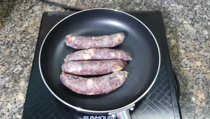 Đặt chảo lên bếp, bật bếp. Cho nước vào chảo, khoảng một nửa chiều cao của lạp xưởng. (45.64, 61.3, 69.62)