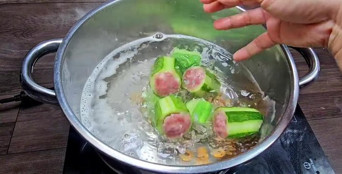 Cho dưa leo nhồi thịt và cà rốt vào nồi canh.