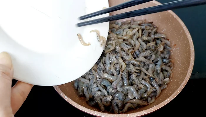 Cho tôm vào chảo (chưa cho mỡ), thêm bột canh, hạt nêm, nước mắm, xì dầu, đường. Đảo đều và đun cho tôm thấm gia vị, đến khi tôm rút hết nước.