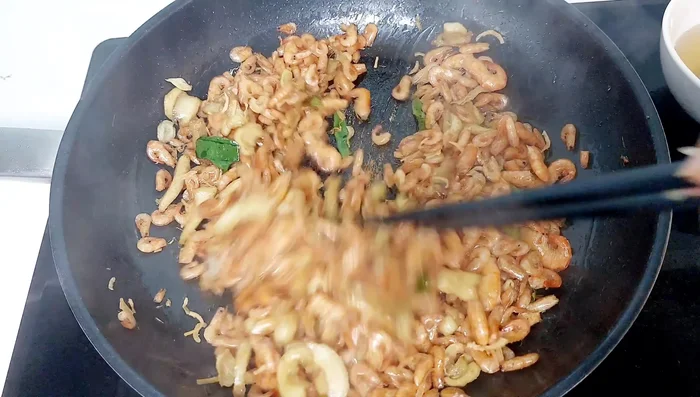 Cho hành phi vào, đảo đều, tắt bếp và múc tôm ra đĩa.