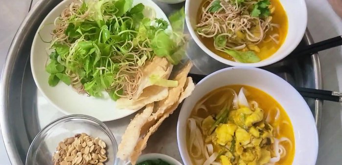 Thêm rau sống, đậu phộng, hành ngò, nước chấm vào tô mì.