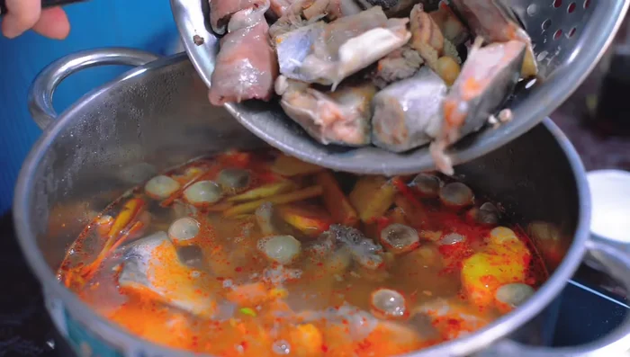 Cho đầu cá vào nước dùng đang sôi, nấu thêm 5 phút cho cá chín. (291.72)